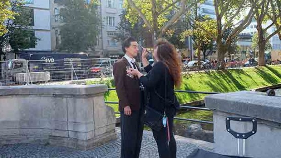 Schauspieler und Maskenbildnerin vor einem Wassergraben.