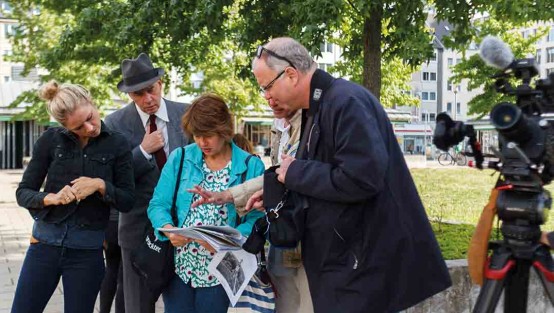 Produktions- und Drehteam bei der Absprache draußen am Drehort mit Kamera.