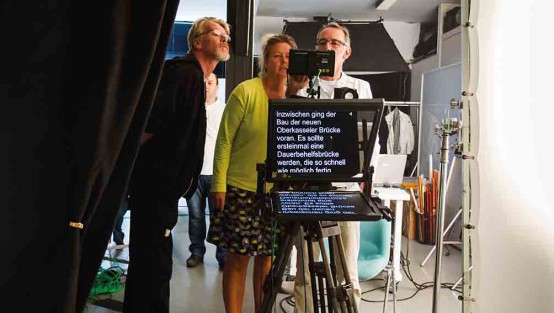  Drehteam hinter einem Teleprompter und Drehtechnik im Studio.