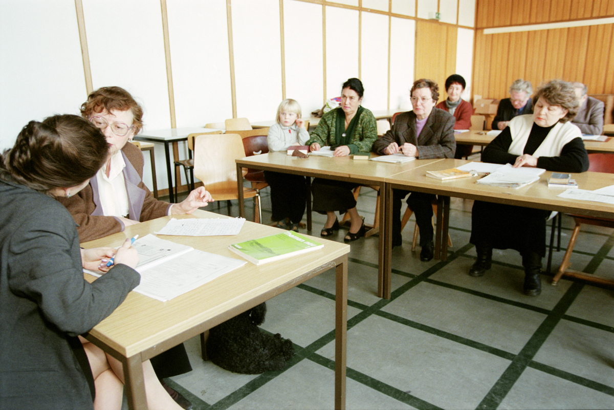 Erwachsene sitzen in einem Klassenzimmer an Schulbänken