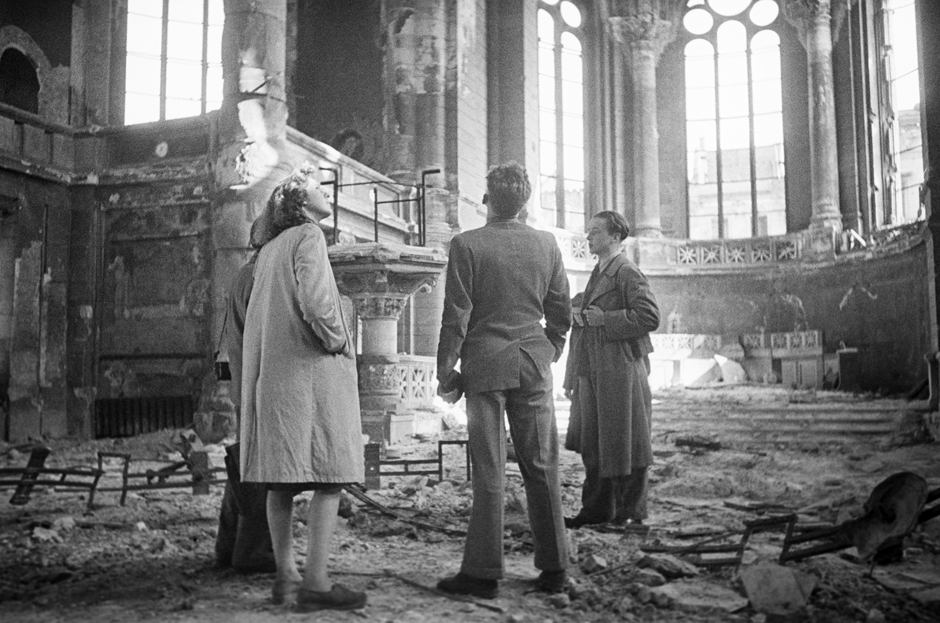 Vier Menschen stehen im Inneren einer Kirche, die beschädigt ist