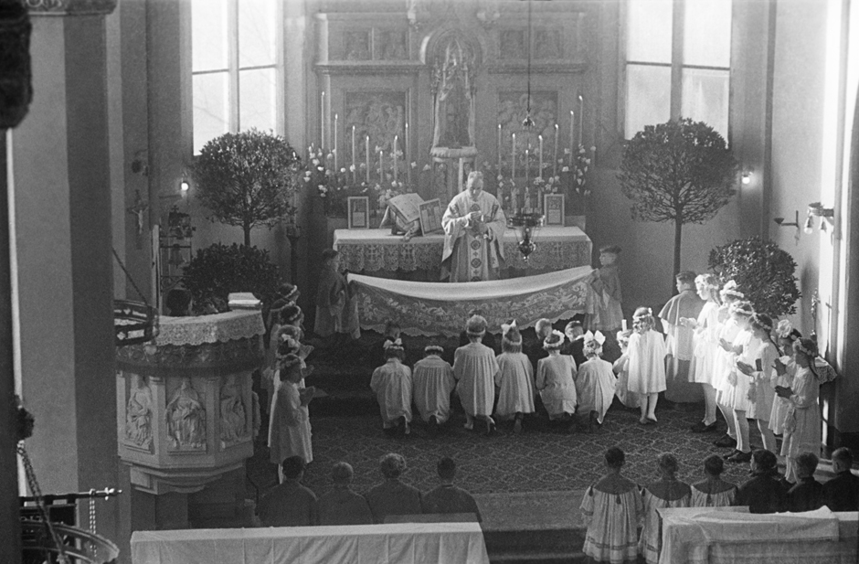 Kommunionkinder knien vor einem Altar