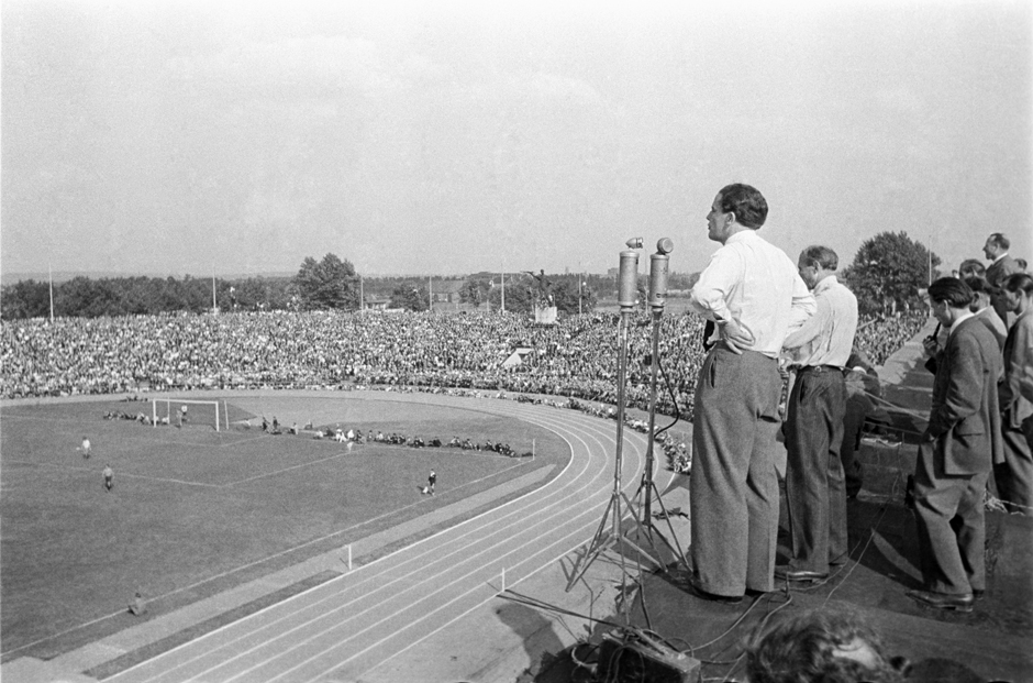 Ein Mann steht in einem Fußballstadion an einem Mikrofon