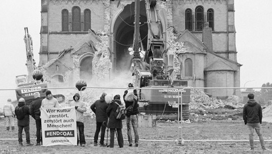 Die Kirche wird abgerissen und Menschen mit Plakaten protestieren dagegen