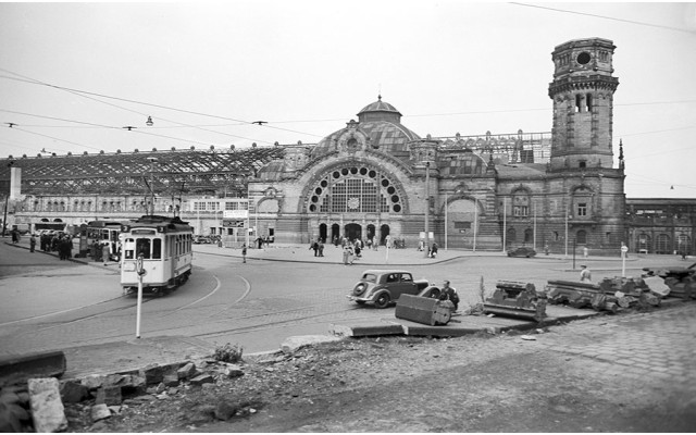 Schwarz-Weiss-Aufnahme einer historische Straßenbahn vor dem noch kriegsbeschädigten Kölner Hauptbahnhof im Jahr 1949