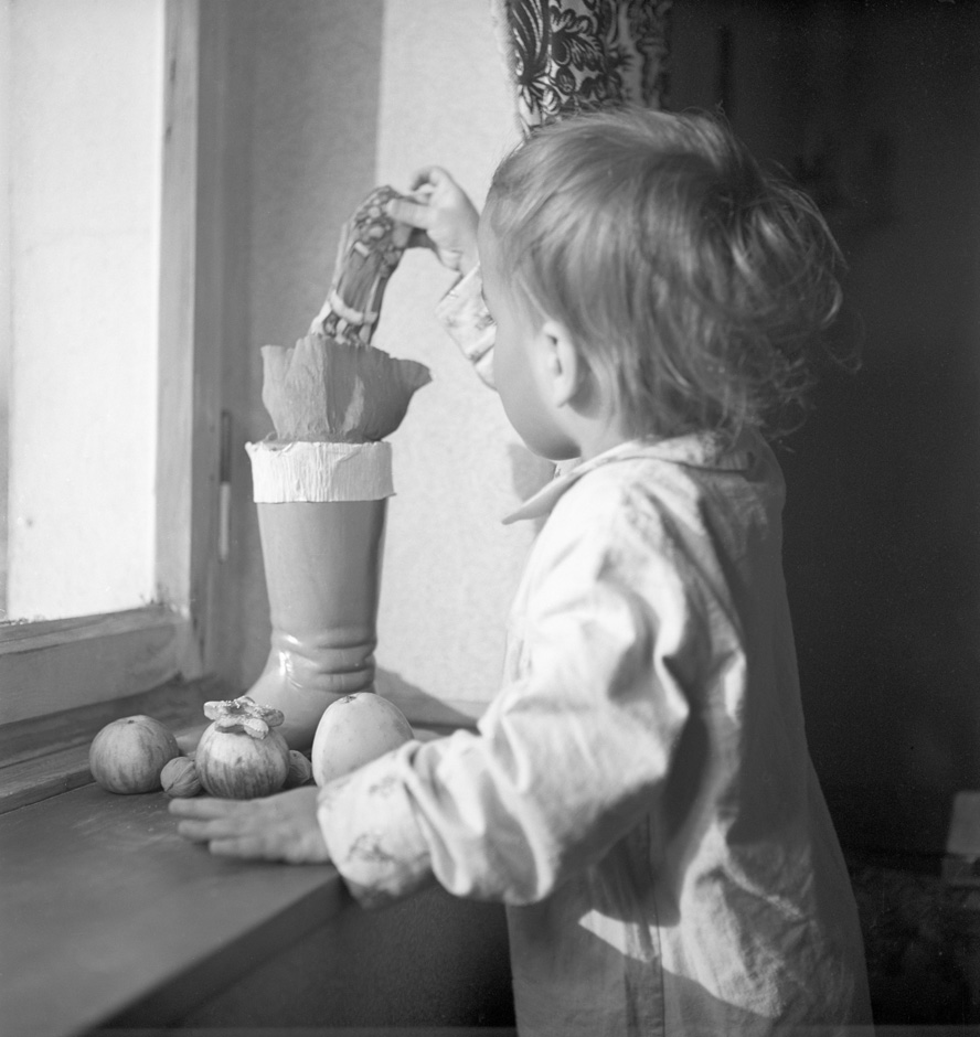 Ein Kind holt Süßigkeiten aus einem Stiefel, der auf einer Fensterbank steht.