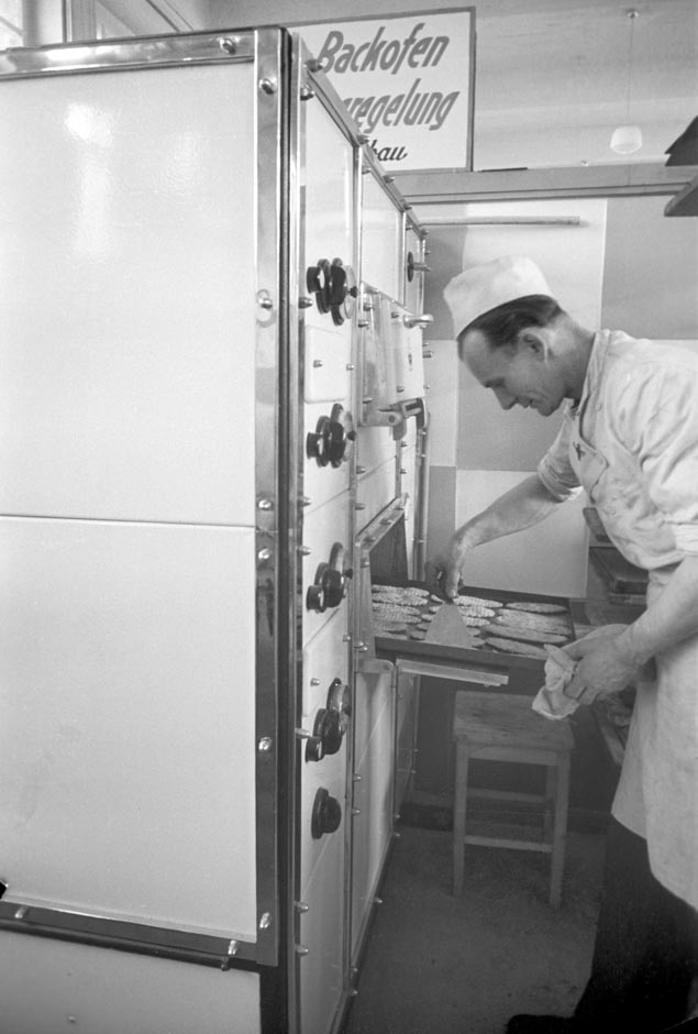 LVR-ZMB, C.A. Stachelscheid Ein Mann steht mit einem Backblech vor einem Backofen.