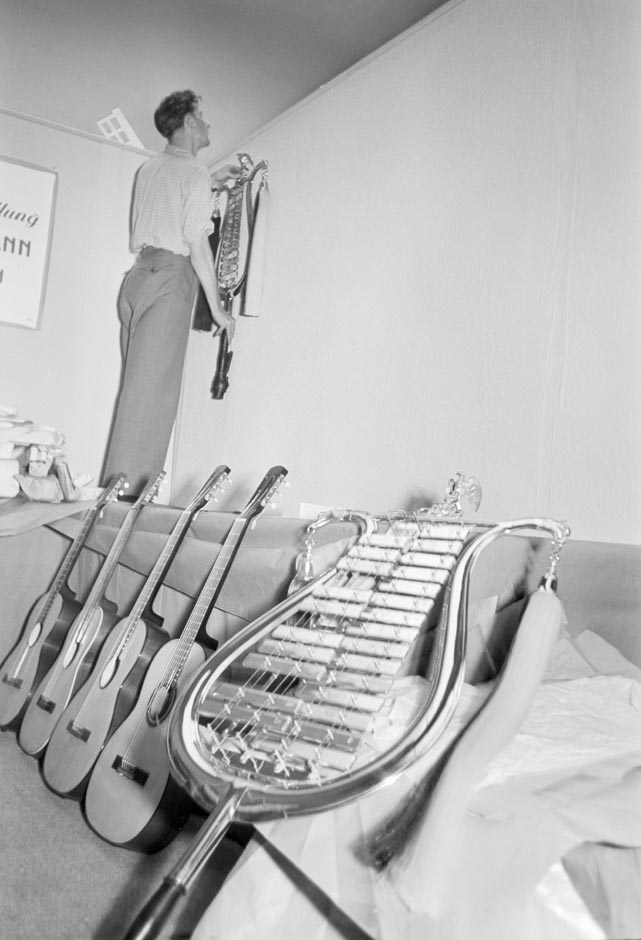 LVR-ZMB, C.A. Stachelscheid Ein Mann hängt ein Musikinstrument an die Wand.
