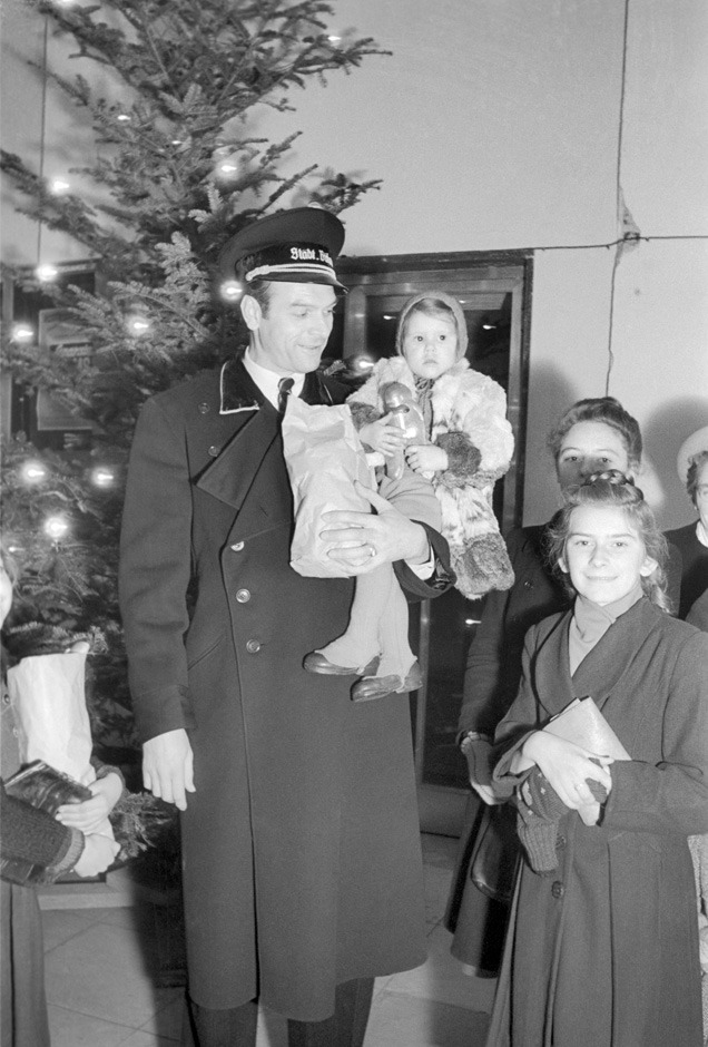 Eine Familie steht vor einem Weihnachtsbaum.