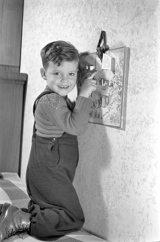 Ein Junge kniet auf einem Bett vor einem Kalender.