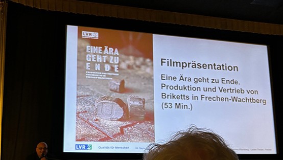 Eine Kinoleinwand und davor ein Sprecher.