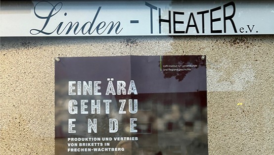 Plakat hängt in einem Schaufenster.