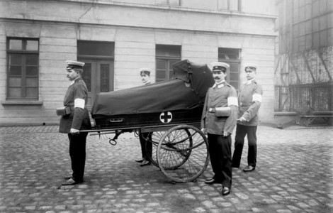 4 Männer in der Mitte ein historischer Krankentransportwagen. Digitalisierung historischer Glasnegative