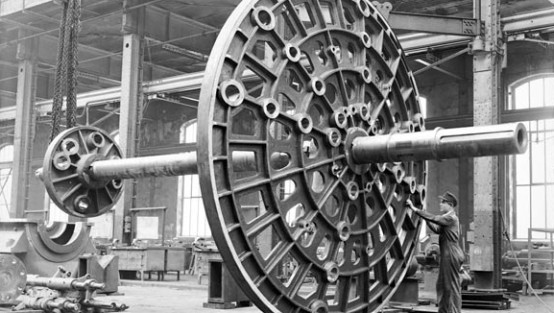 Ein Arbeiter steht neben einem meterhohen Jochrahmen, der bei der Kabel- und Drahtherstellung zum Einsatz kommt