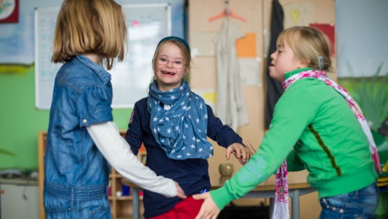 Drei Mädchen bilden Hand in Hand einen Kreis.
