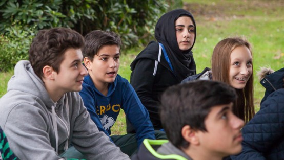 Eine Schülergruppe sitzt auf einem Rasen.