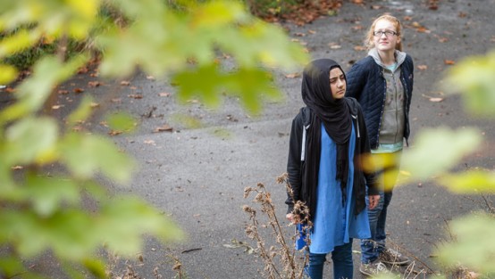 Zwei Mädchen stehen auf einem Weg und schauen sich um.