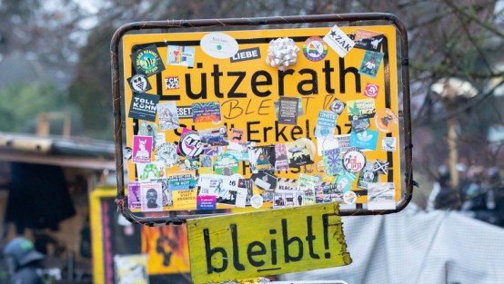 Räumung Lützerath, Polizei und Aktivisten vor Ortsschild in Lützerath