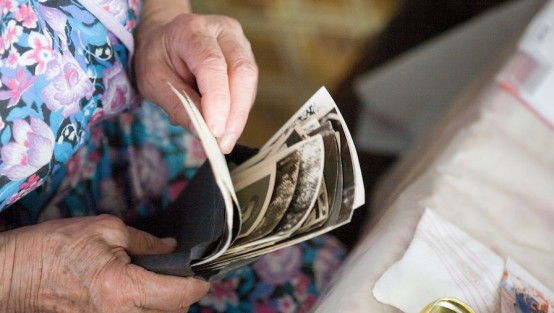 Frauenhände, die einen Stapel alter Schwarzweissfotos durchblättern