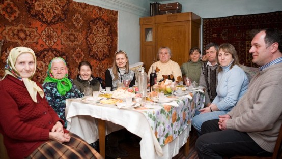 Frauen und Männer sitzen lächelnd um einen reich gedeckten Esstisch