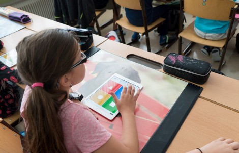 Mädchen sitzt am Schreibtisch, auf dem ein Tablet liegt